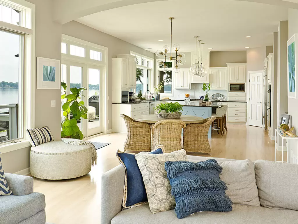 Coastal style family, dining room and kitchen with neutral colored finishes and blue fabric accents